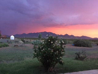 Photo of a colorful sunset behind the mountains and a white observatory building.