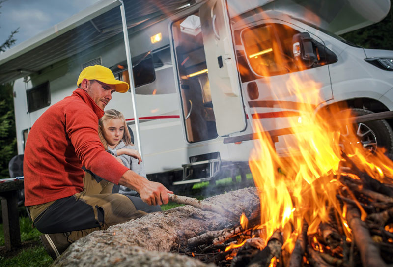 Family building a fire outside of RV