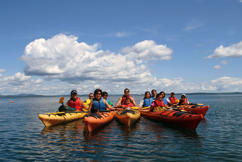 Group of diverse people in kayaks on a lake in Maine