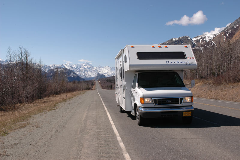 Class C motorhome driving on a road with mountains in background