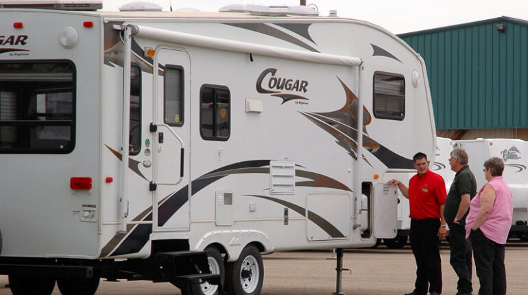 RV sales person showing a fifth-wheel to customers