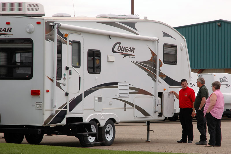 RV sales person showing a fifth-wheel to customers